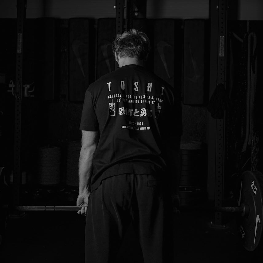 Homme faisant du soulevé de terre avec un t-shirt oversize noir TOSHI inspiré de l’univers du manga Demon Slayer.
