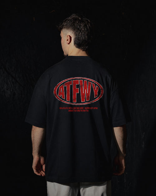 Homme de dos portant un t-shirt oversize de couleur noire, avec un visuel des lettres ATFWY en rouge, destiné aux athlètes et inspiré de la culture japonaise.