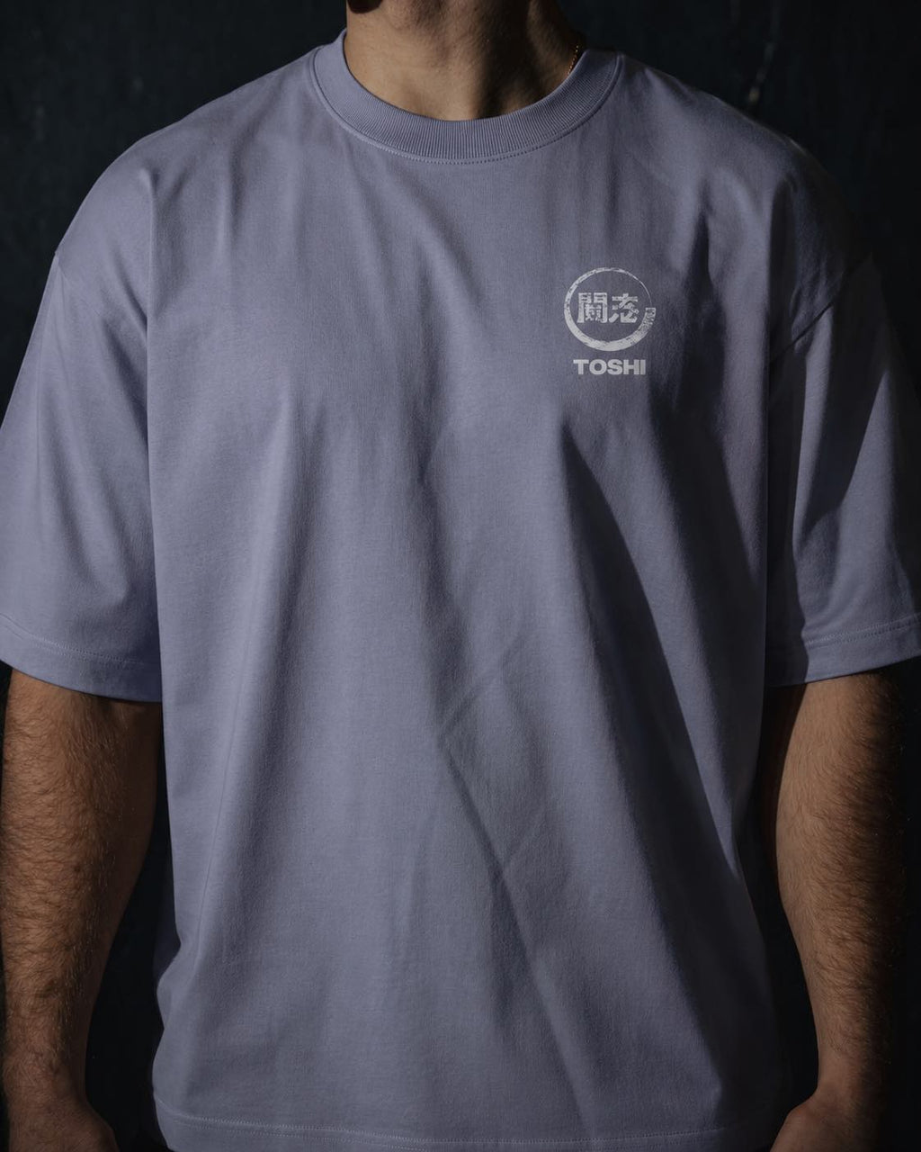 Homme de face portant un t-shirt oversize de couleur violette, avec un logo japonais rouge de la marque TOSHI inspiré des mangas et animes.