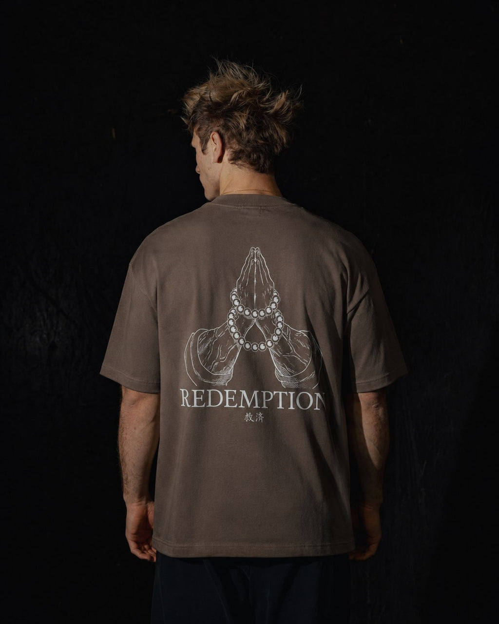 Homme de dos portant un t-shirt oversize de couleur mocha, avec un visuel inspiré de l’anime demon slayer, représentant les mains du pilier Gyomei.