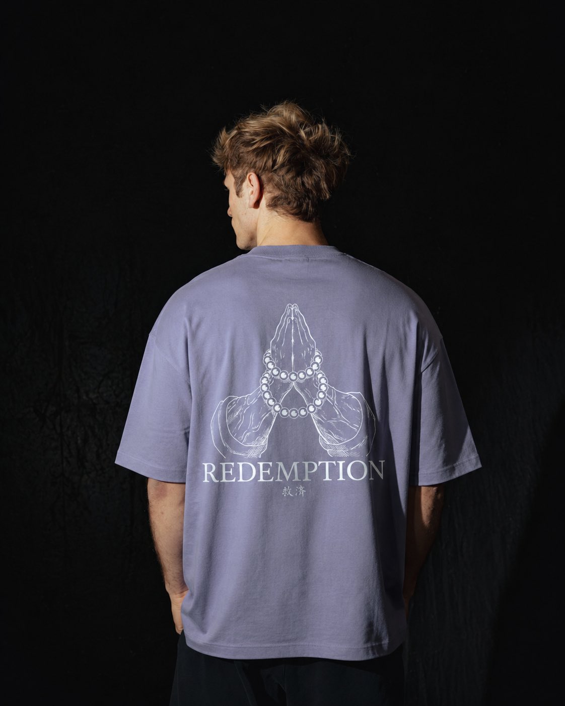 Homme de dos portant un t-shirt oversize de couleur violette, avec un visuel inspiré de l’anime demon slayer, représentant les mains du pilier Gyomei.